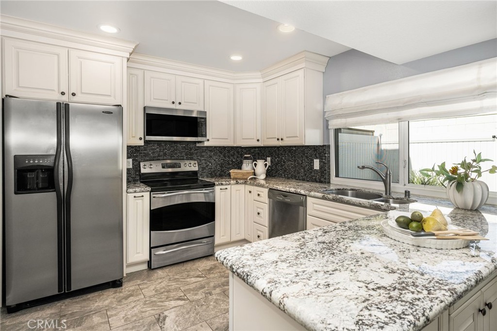 Generous cabinetry and a granite-topped island provide abundant space for meal preparation and storage. - 6931 Danvers Dr, Garden Grove CA 92845 - photo 18