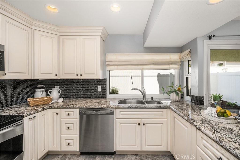 A bright kitchen workspace features expansive granite counters and a window above the sink. - 6931 Danvers Dr, Garden Grove CA 92845 - photo 19