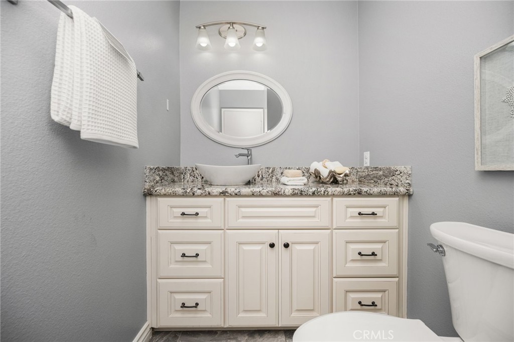 Guest bathroom Beautiful granite, a stylish vessel sink, and a decorative round mirror add an elegant touch. - 6931 Danvers Dr, Garden Grove CA 92845 - photo 28