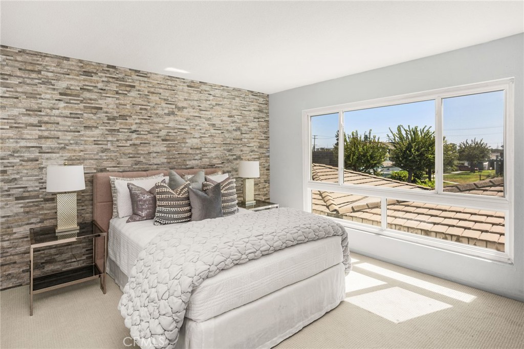 Primary Bedroom: A beautiful stone accent wall sets the tone for this spacious, sun-filled retreat, featuring generous w - 6931 Danvers Dr, Garden Grove CA 92845 - photo 32