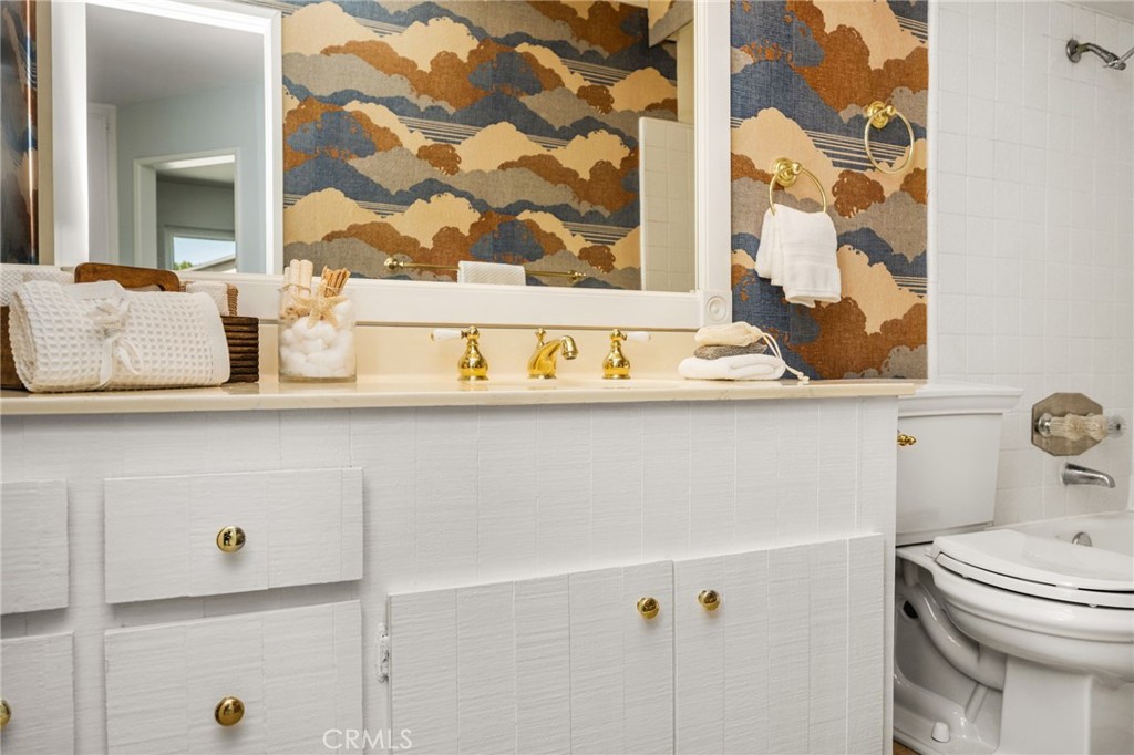 Guest bathroom Charming guest vanity with ample cabinet storage, a large mirror, and gold-tone fixtures. - 6931 Danvers Dr, Garden Grove CA 92845 - photo 45