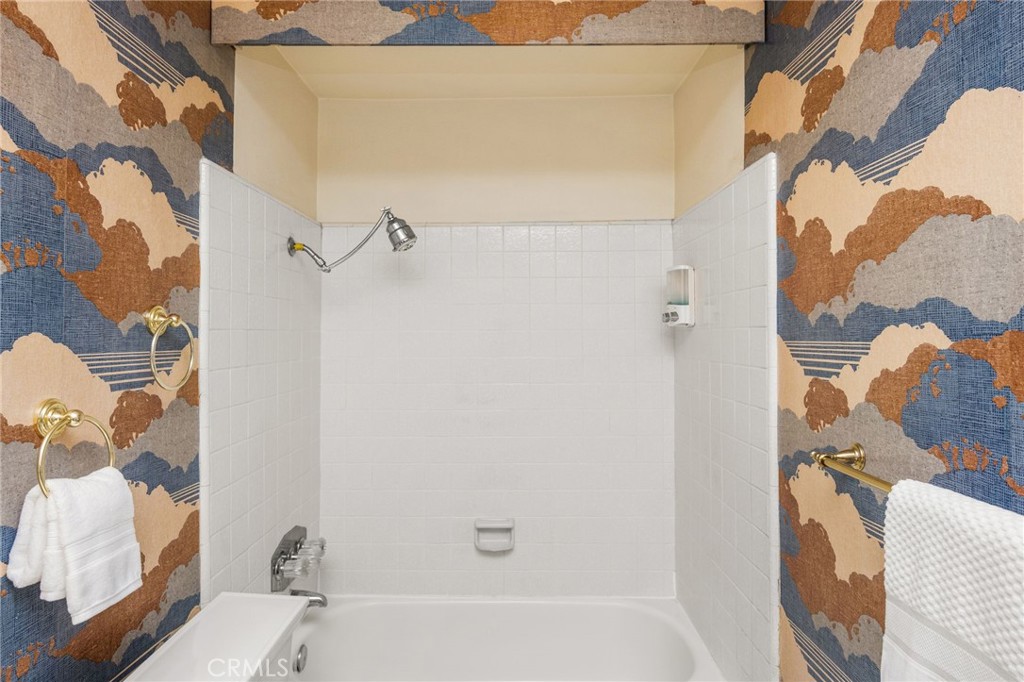 – Guest bath Guest bath features a tiled tub/shower combination framed by distinctive patterned wallpaper. - 6931 Danvers Dr, Garden Grove CA 92845 - photo 46