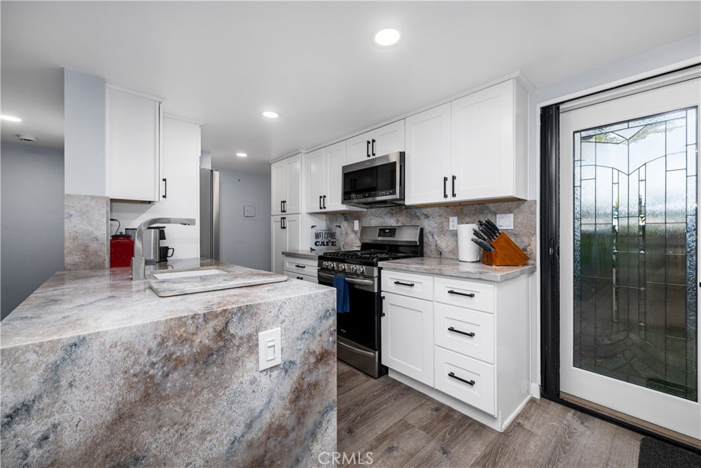 Quartz counters, stained glass french doors to babk patio, exit to garage abour center of picture. Luxury vinal plank fl - 6971 Knollcrest #48 48, Garden Grove CA 92845 - photo 17