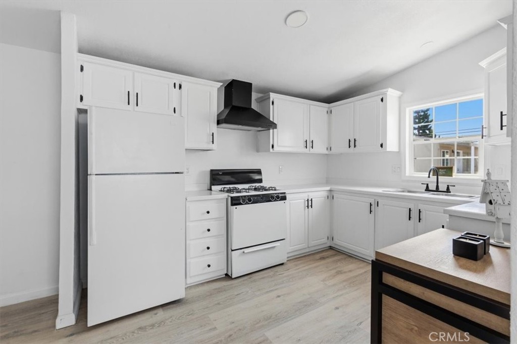 Bright kitchen featuring white cabinetry, gas range, refrigerator, ample storage, and a window overlooking the outdoor a - 7887 Lampson Ave Avenue 10, Garden Grove CA 92841 - photo 4