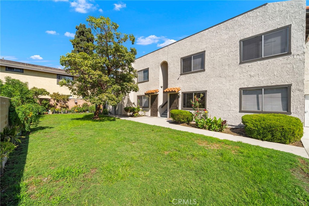 The freshly painted two-story exterior overlooks a green lawn bordered by established landscaping. - 9941 11th Street, Garden Grove CA 92844 - photo 6