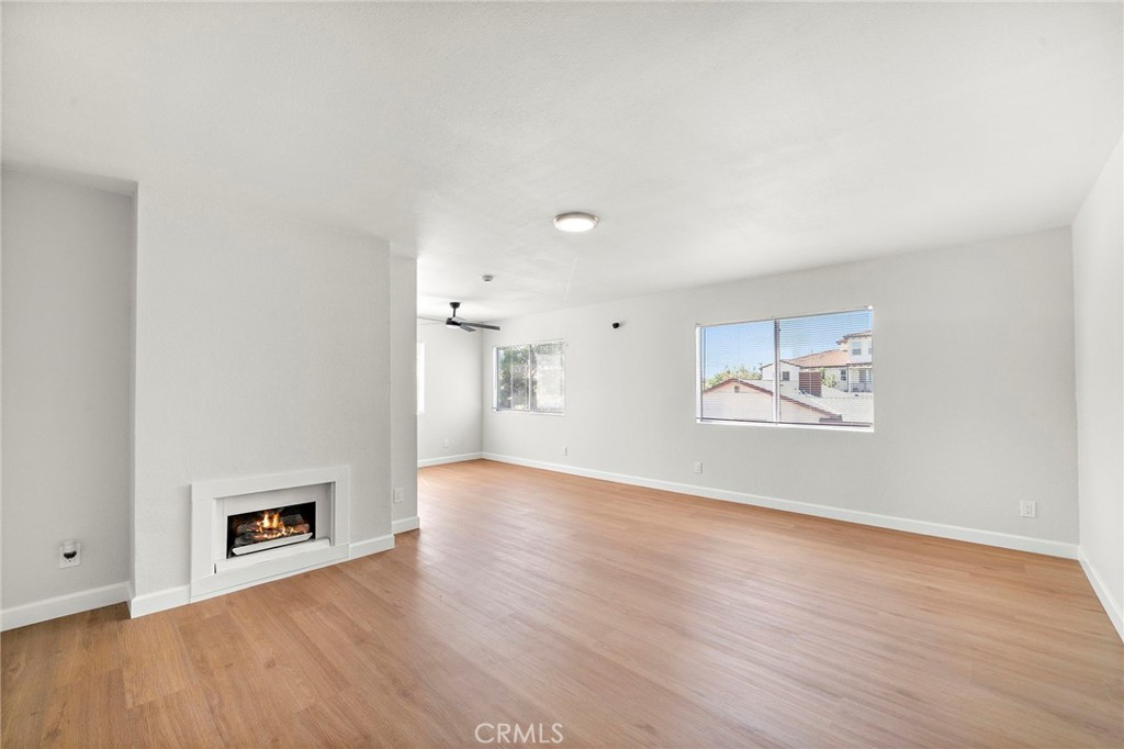 Unit C The bright living room features wood-look flooring, a fireplace, and an open connection to the kitchen. - 9941 11th Street, Garden Grove CA 92844 - photo 8