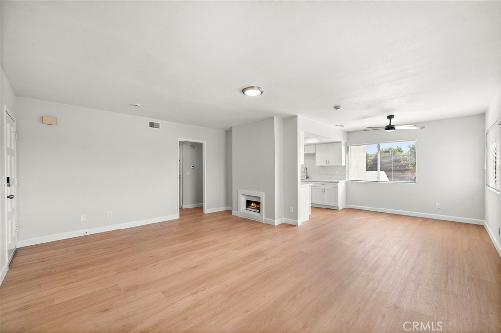 This spacious living area combines fresh white walls, warm wood-look flooring, and an open kitchen pass-through. - 9941 11th Street, Garden Grove CA 92844 - photo 9