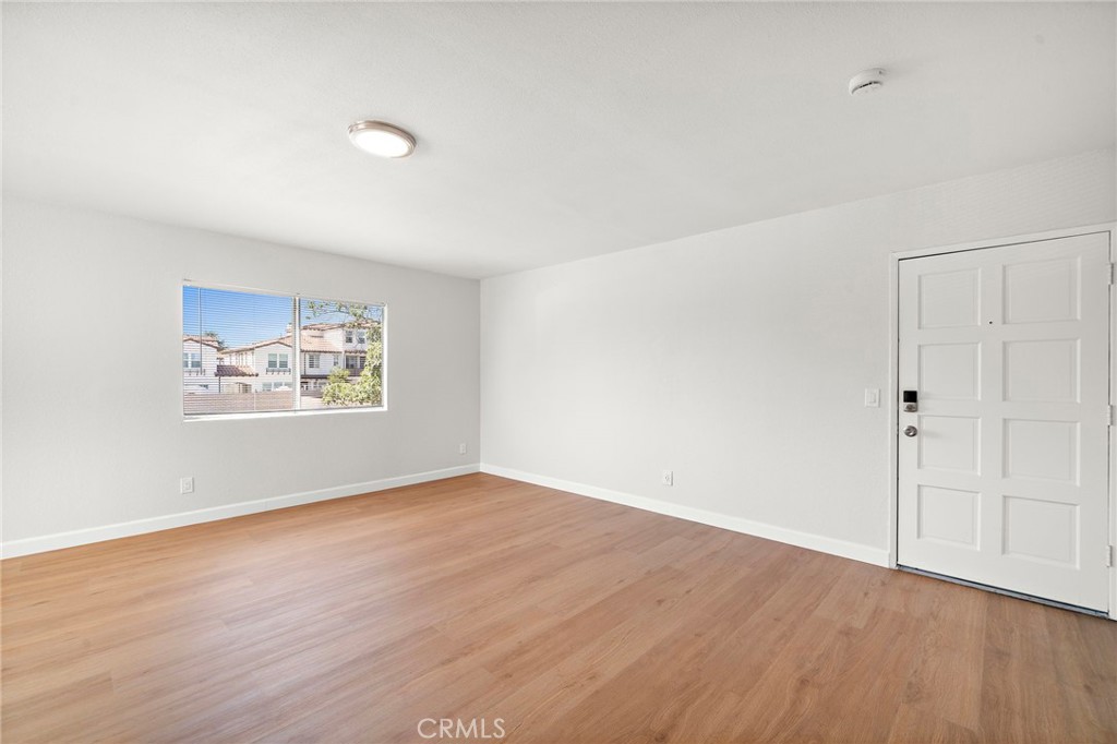 The living room offers a versatile layout with a wide window, clean white walls, and ample open floor space. - 9941 11th Street, Garden Grove CA 92844 - photo 11