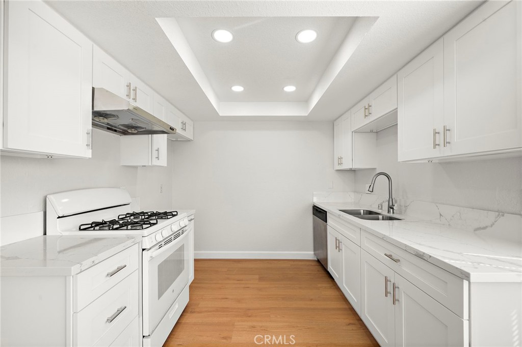 The remodeled kitchen showcases white cabinetry, light quartz countertops, recessed lighting, and a gas range. - 9941 11th Street, Garden Grove CA 92844 - photo 14