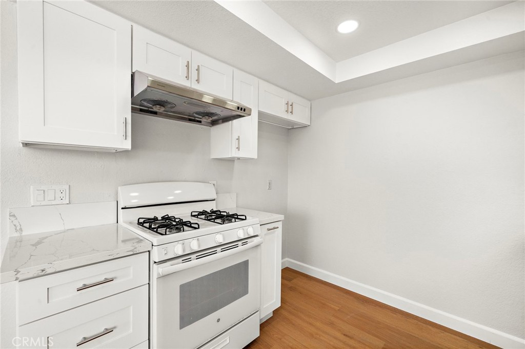 The gas range and stainless-steel hood complement the kitchen’s white cabinetry and streamlined finishes. - 9941 11th Street, Garden Grove CA 92844 - photo 17