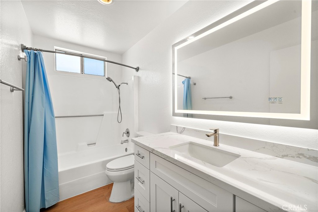 The remodeled bathroom pairs a broad vanity and illuminated mirror with a tub-and-shower combination. - 9941 11th Street, Garden Grove CA 92844 - photo 20