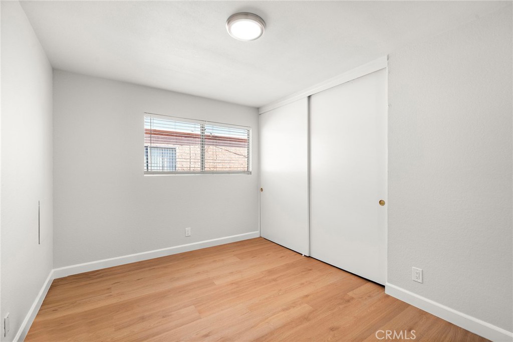 This comfortable bedroom combines a sunlit window, wood-look flooring, and a spacious sliding-door closet. - 9941 11th Street, Garden Grove CA 92844 - photo 21