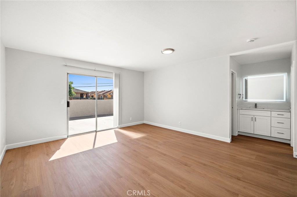Natural light fills this generous room through the balcony slider, with a bathroom visible beyond the adjacent doorway. - 9941 11th Street, Garden Grove CA 92844 - photo 24