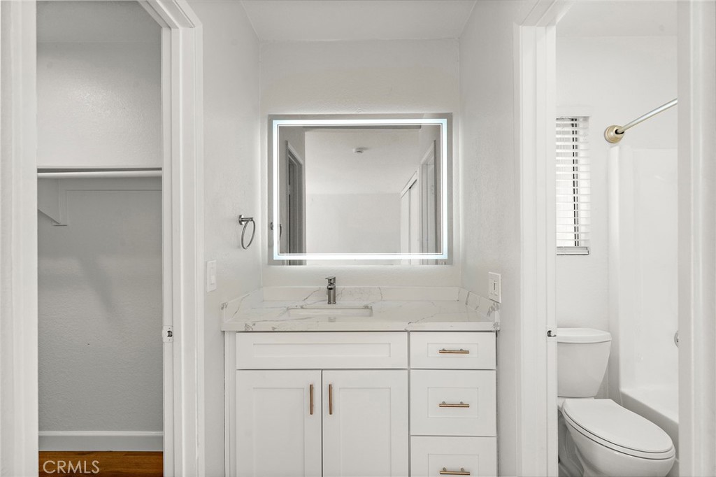 The updated bathroom features a white vanity, illuminated mirror, and a bright, coordinated finish. - 9941 11th Street, Garden Grove CA 92844 - photo 26
