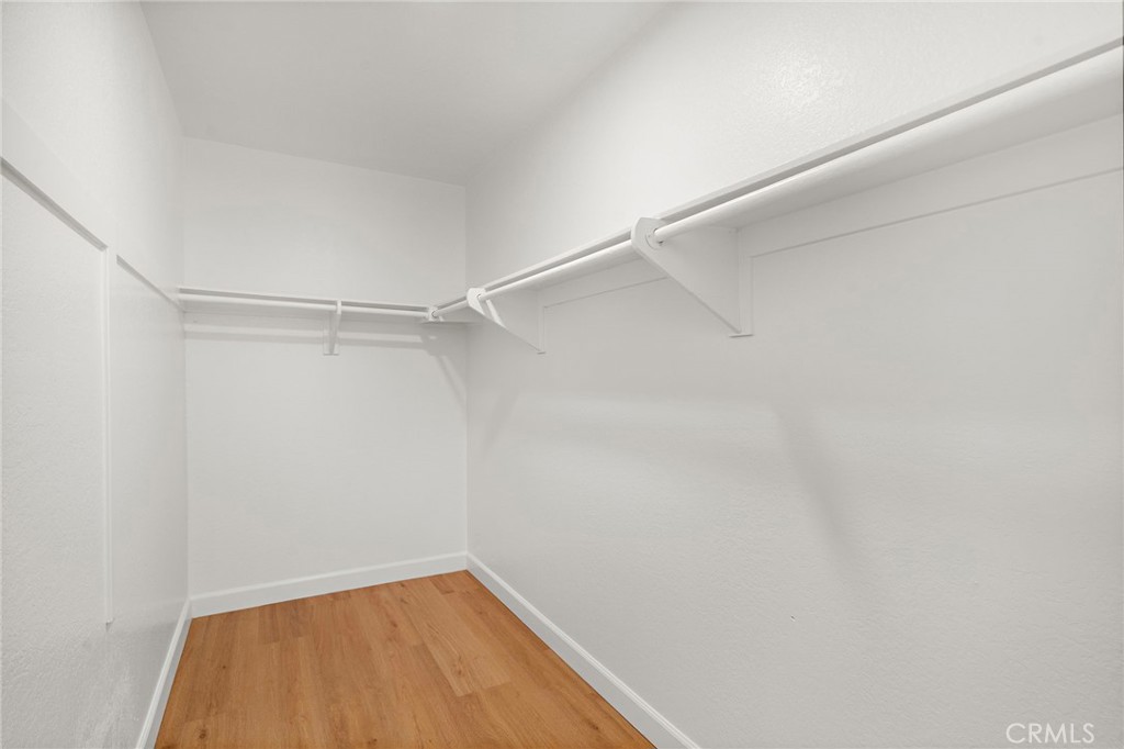 A walk-in closet provides hanging space on multiple sides above matching wood-look flooring. - 9941 11th Street, Garden Grove CA 92844 - photo 27