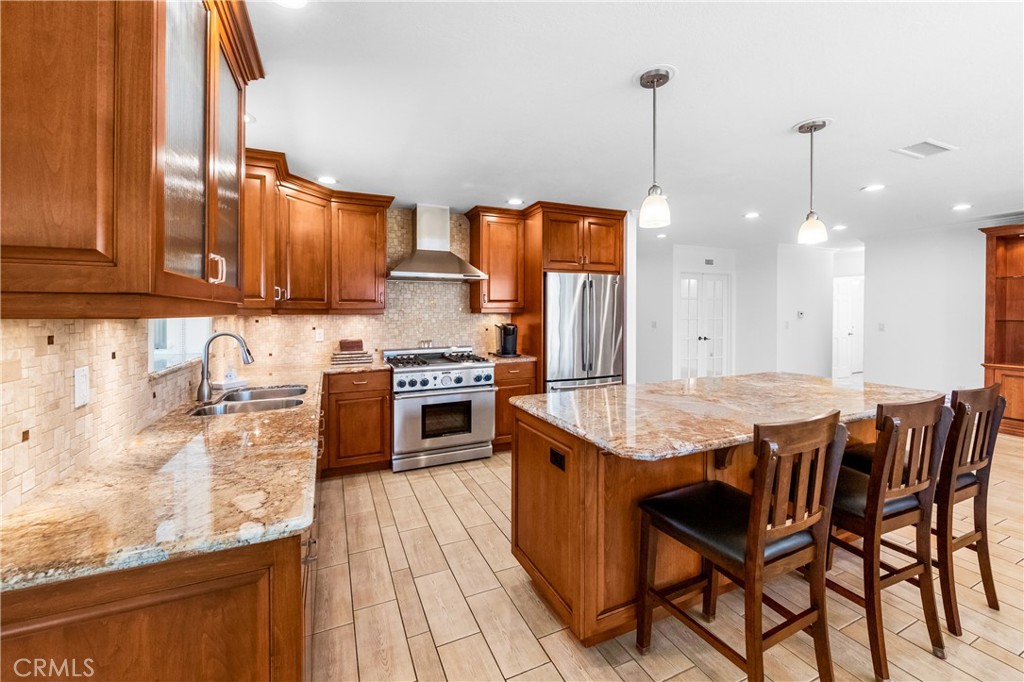 Kitchen and dining area with wood cabinetry, center island, and natural light. - 17042 Friml Lane, Huntington Beach CA 92649 - photo 12