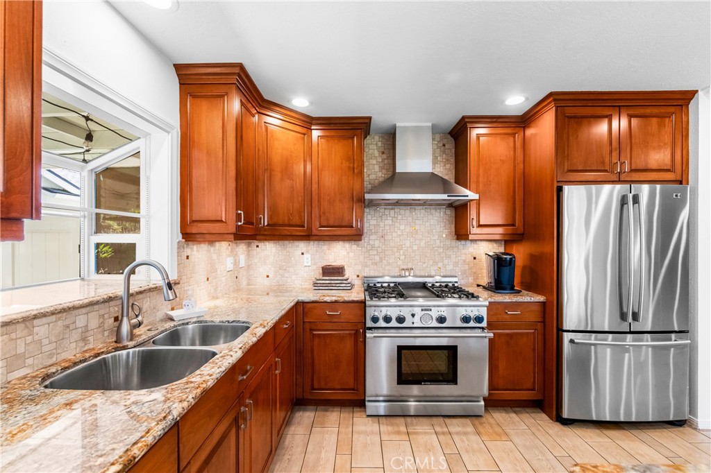 Kitchen features stainless-steel appliances, wood cabinetry, and ample preparation space. - 17042 Friml Lane, Huntington Beach CA 92649 - photo 13