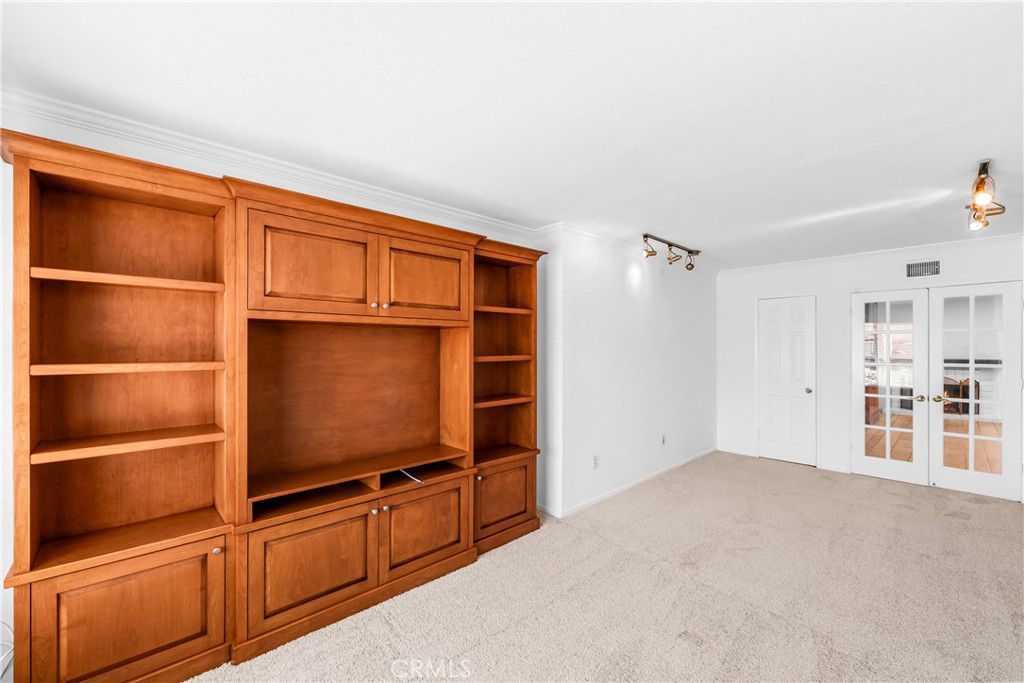 Spacious bedroom 1 featuring built-in wood cabinetry and shelving for storage and display. - 17042 Friml Lane, Huntington Beach CA 92649 - photo 19