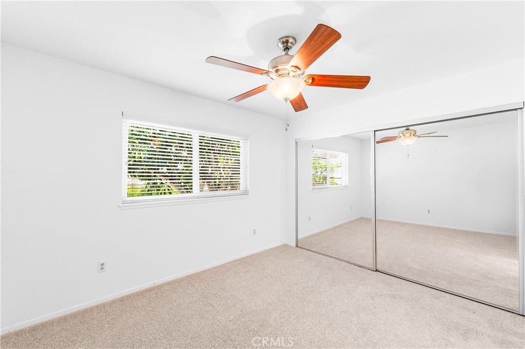 Primary bedroom featuring a ceiling fan and large window. - 17042 Friml Lane, Huntington Beach CA 92649 - photo 31