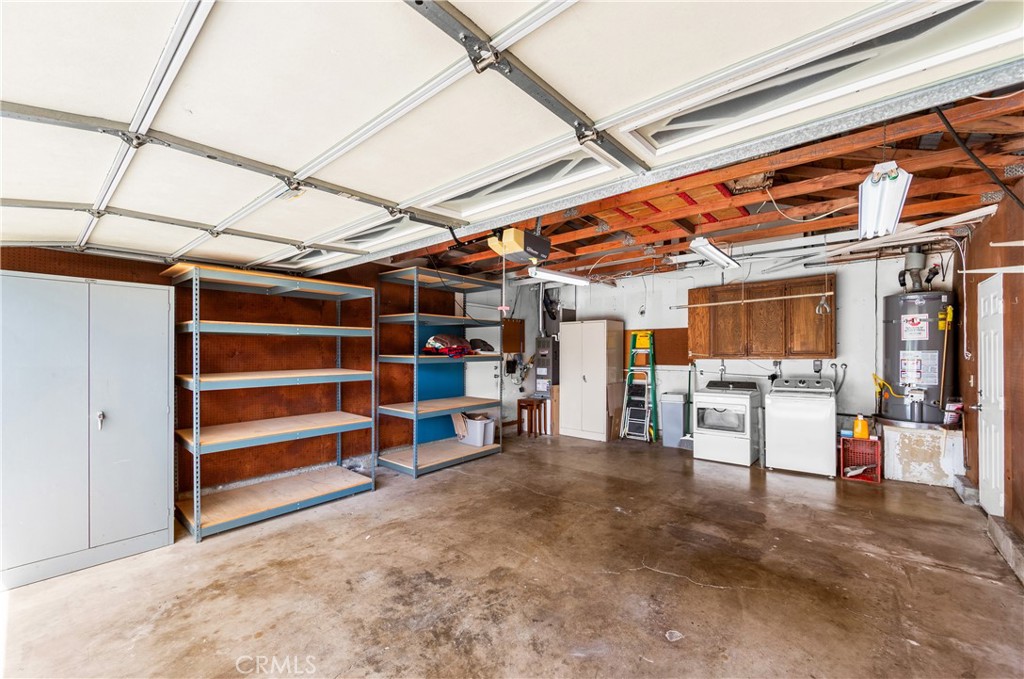 Large garage with extensive storage, work areas, and built-in cabinetry. - 17042 Friml Lane, Huntington Beach CA 92649 - photo 43