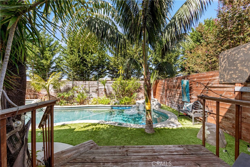 Resort-inspired backyard featuring a sparkling pool and lush tropical landscaping. - 17327 Apel Lane, Huntington Beach CA 92649 - photo 11