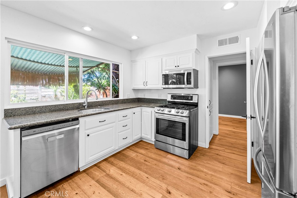 Modern kitchen with bright cabinetry, stainless-steel appliances and beautiful landscape views. - 17327 Apel Lane, Huntington Beach CA 92649 - photo 15