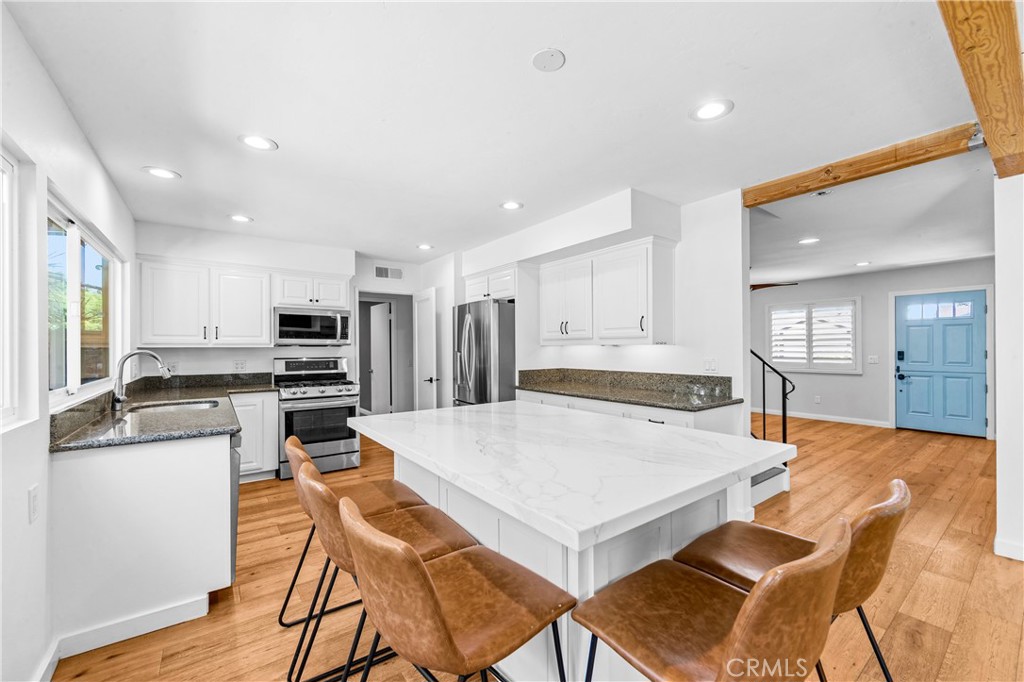 Open kitchen and dining area with island, modern appliances and poolside views. - 17327 Apel Lane, Huntington Beach CA 92649 - photo 19