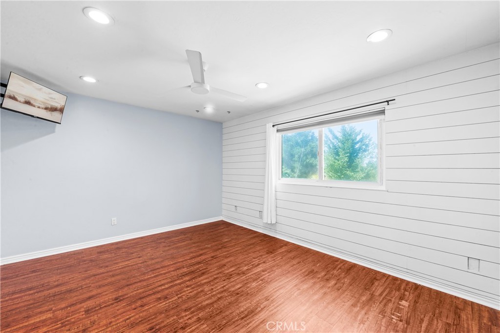 Bright secondary bedroom with wood-style flooring and natural light. - 17327 Apel Lane, Huntington Beach CA 92649 - photo 21