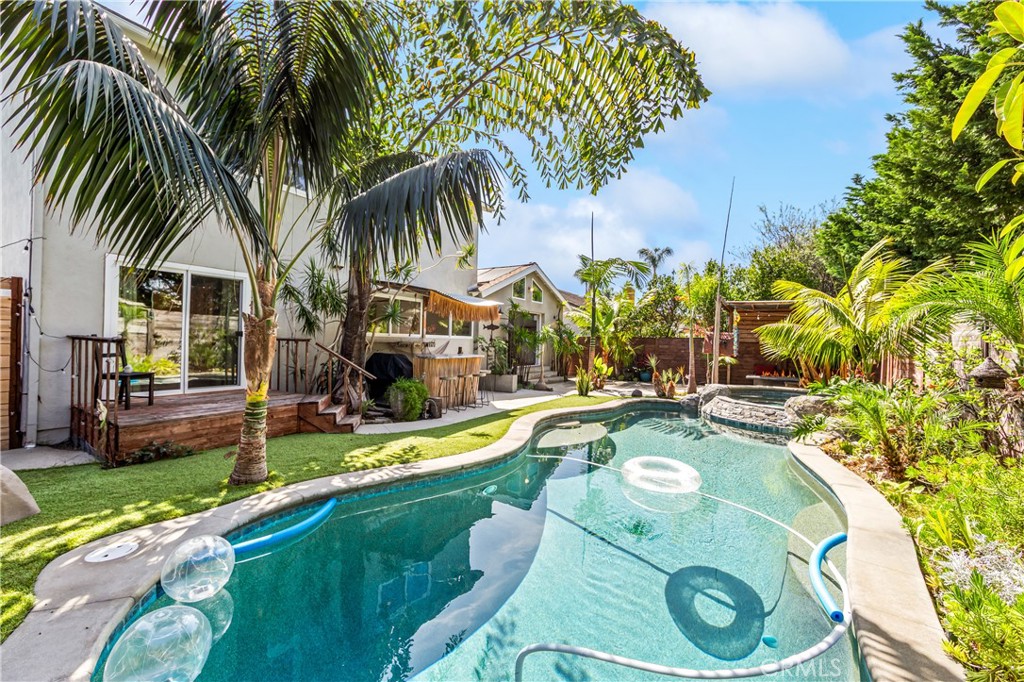 Inviting pool retreat surrounded by palms and vibrant landscaping. - 17327 Apel Lane, Huntington Beach CA 92649 - photo 27