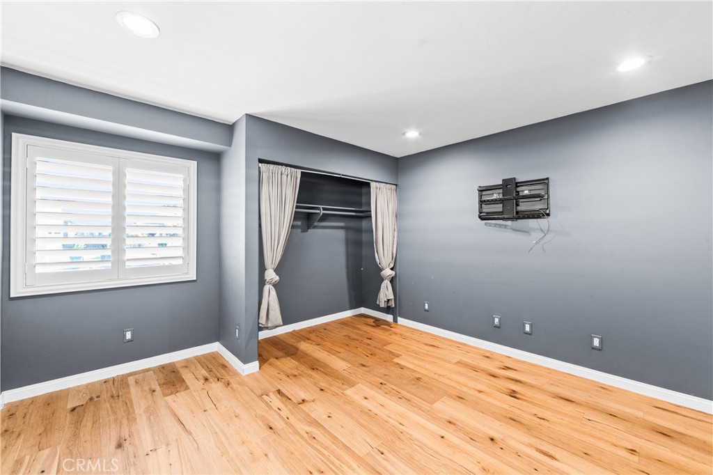 Bright bedroom featuring wood flooring, plantation shutters and ceiling fan. - 17327 Apel Lane, Huntington Beach CA 92649 - photo 40