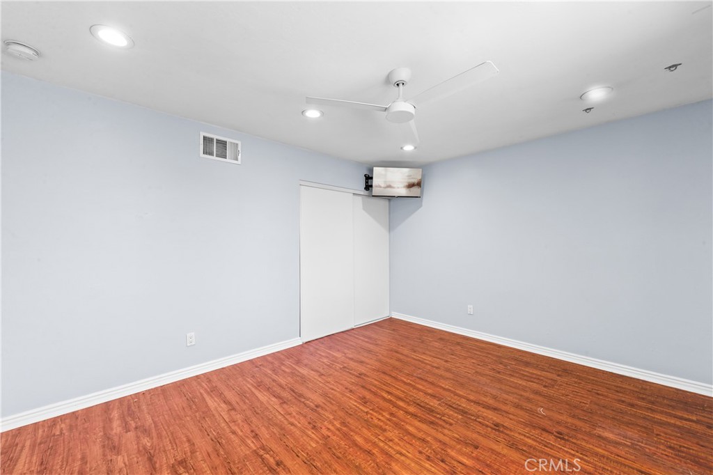 Comfortable bedroom with warm wood flooring, recessed lighting and ceiling fan. - 17327 Apel Lane, Huntington Beach CA 92649 - photo 46