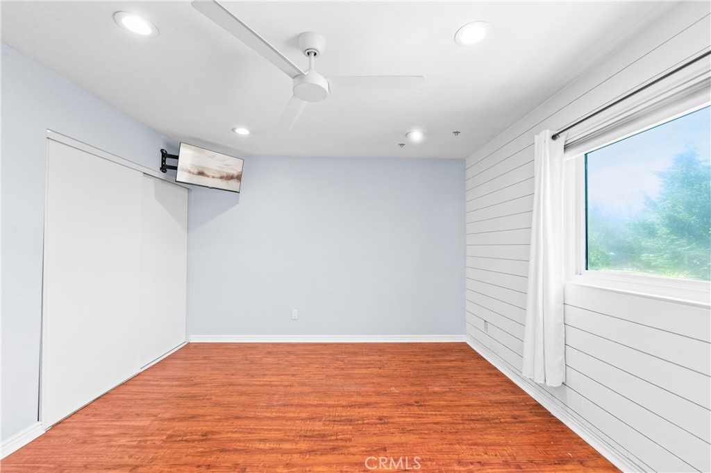 Spacious bedroom with wood flooring, ceiling fan and generous natural light. - 17327 Apel Lane, Huntington Beach CA 92649 - photo 48
