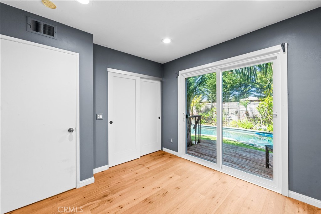 Bright bedroom with wood flooring, glass door overlooking the outdoor retreat. - 17327 Apel Lane, Huntington Beach CA 92649 - photo 52