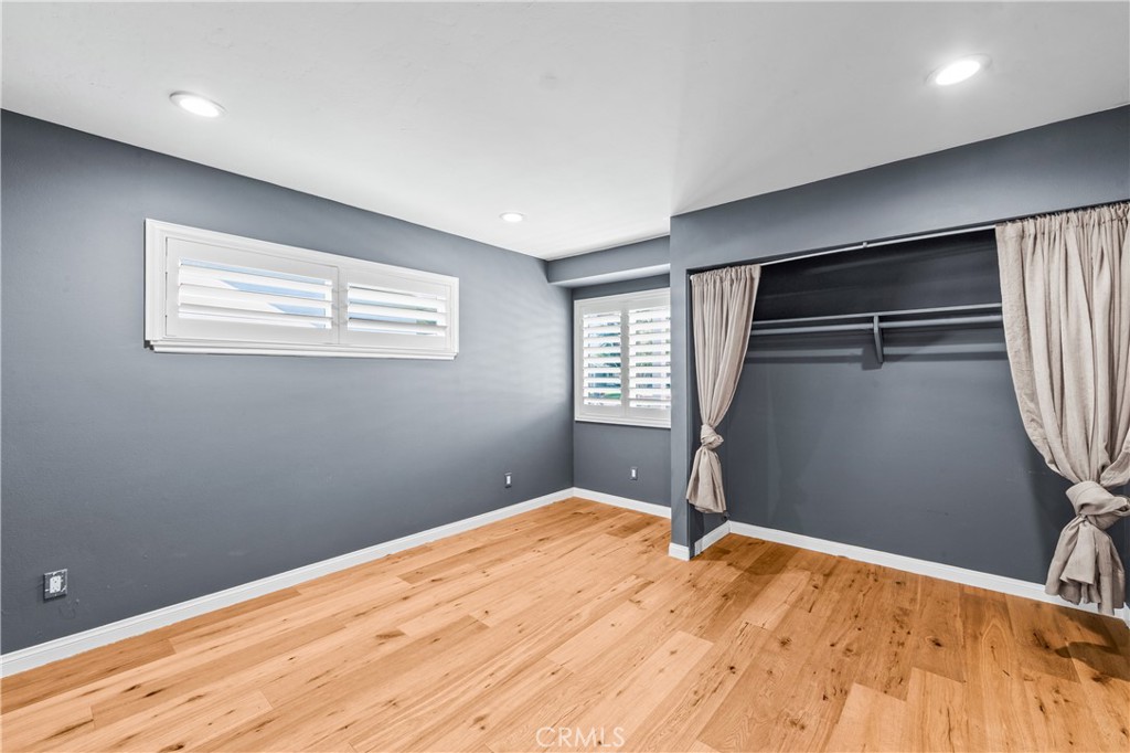 Inviting bedroom with wood floors, ceiling fan and abundant natural light. - 17327 Apel Lane, Huntington Beach CA 92649 - photo 53