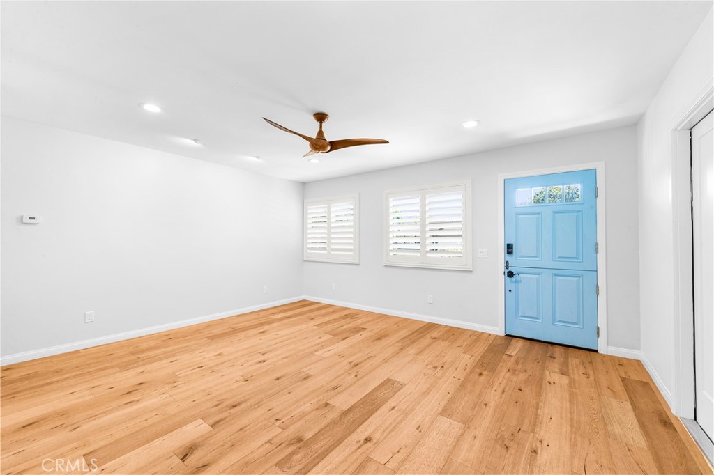 Bright open living area with elegant wood flooring and contemporary ceiling fan. - 17327 Apel Lane, Huntington Beach CA 92649 - photo 55