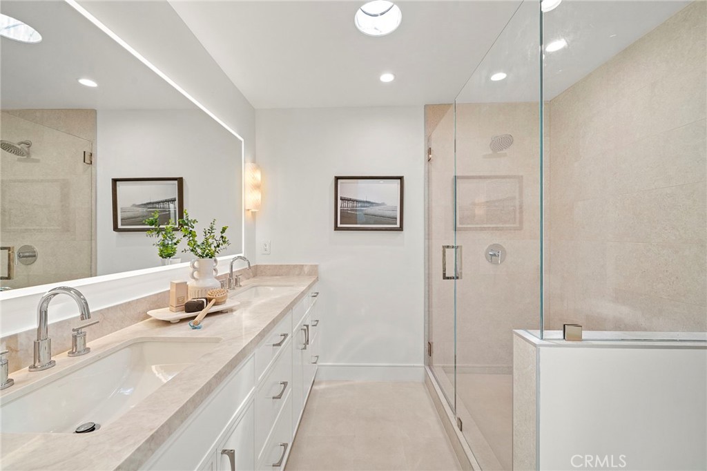 Primary suite bathroom with dual sinks, quartz countertops, custom cabinetry, sconce lighting, and oversized walk-in sho - 20852 Farnsworth Lane, Huntington Beach CA 92646 - photo 22