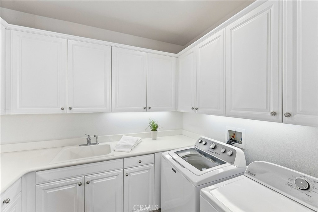 Upstairs inside laundry room with wrap around counter space and an abundance of storage cabinetry. - 21306 Balerma, Huntington Beach CA 92648 - photo 49