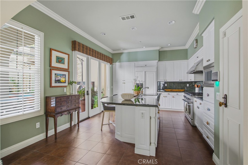 Kitchen with white cabinetry, granite counter tops, stainless steel gas range with dual oven, stainless steel vent hood, - 21322 Balerma, Huntington Beach CA 92648 - photo 3