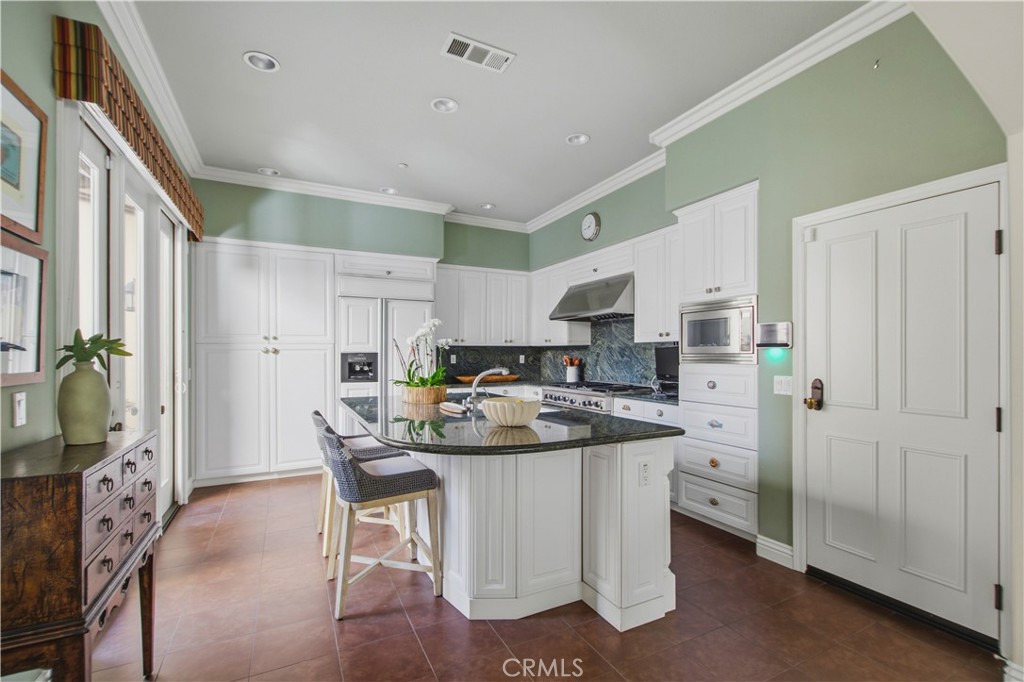 Kitchen with white cabinetry, large pantry with pull out drawers, granite counter tops, paneled refrigerator matching th - 21322 Balerma, Huntington Beach CA 92648 - photo 4