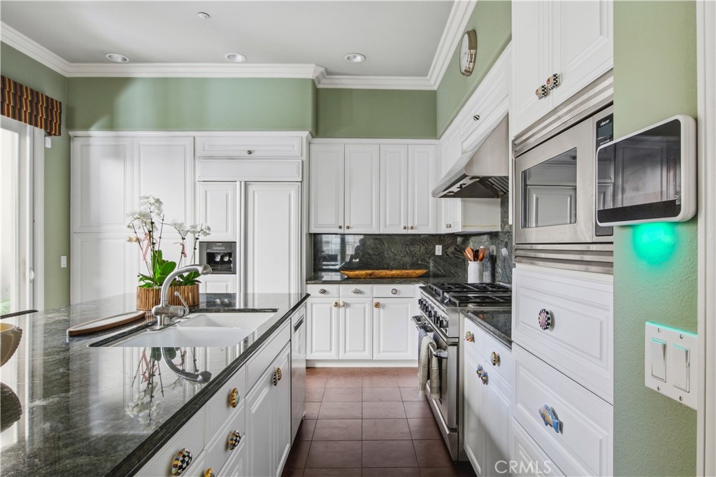 Kitchen with white cabinetry, large pantry with pull out drawers, granite counter tops and back splash, paneled refriger - 21322 Balerma, Huntington Beach CA 92648 - photo 6