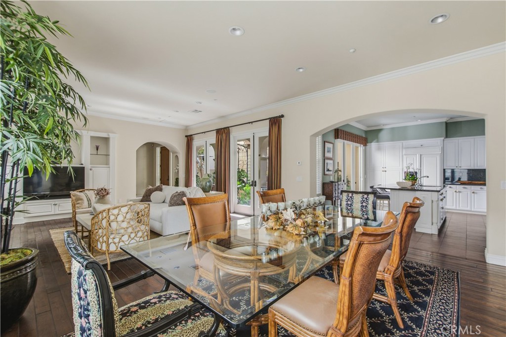 Dining area into living room space with recessed lighting, crown molding, dark wood flooring and archway into kitchen, F - 21322 Balerma, Huntington Beach CA 92648 - photo 8