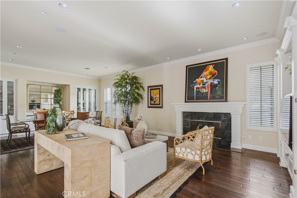 Living room with recessed lighting, crown molding, dark wood flooring, white fireplace, mantle and tile, large windows w - 21322 Balerma, Huntington Beach CA 92648 - photo 9