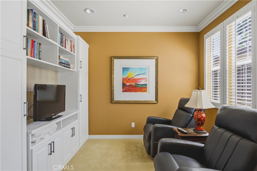 Upper-level Primary Bedroom separate seating area with carpet, built-ins, plantation shutters and recessed lighting. - 21322 Balerma, Huntington Beach CA 92648 - photo 18