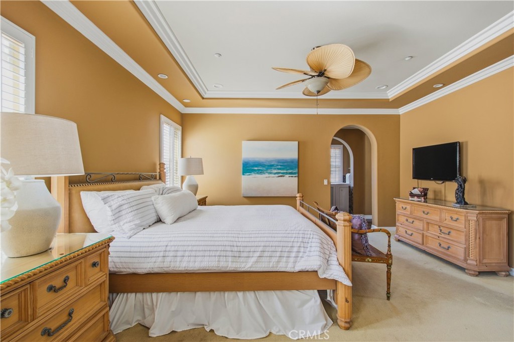 Upper-level Primary bedroom with carpet, large tray ceiling with layered crown molding, large ceiling fan with light and - 21322 Balerma, Huntington Beach CA 92648 - photo 20