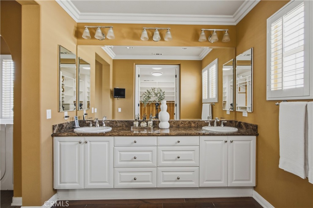 Spacious primary dual sink vanity, granite countertops, white cabinetry, expansive mirrors, decorative lighting, crown m - 21322 Balerma, Huntington Beach CA 92648 - photo 25