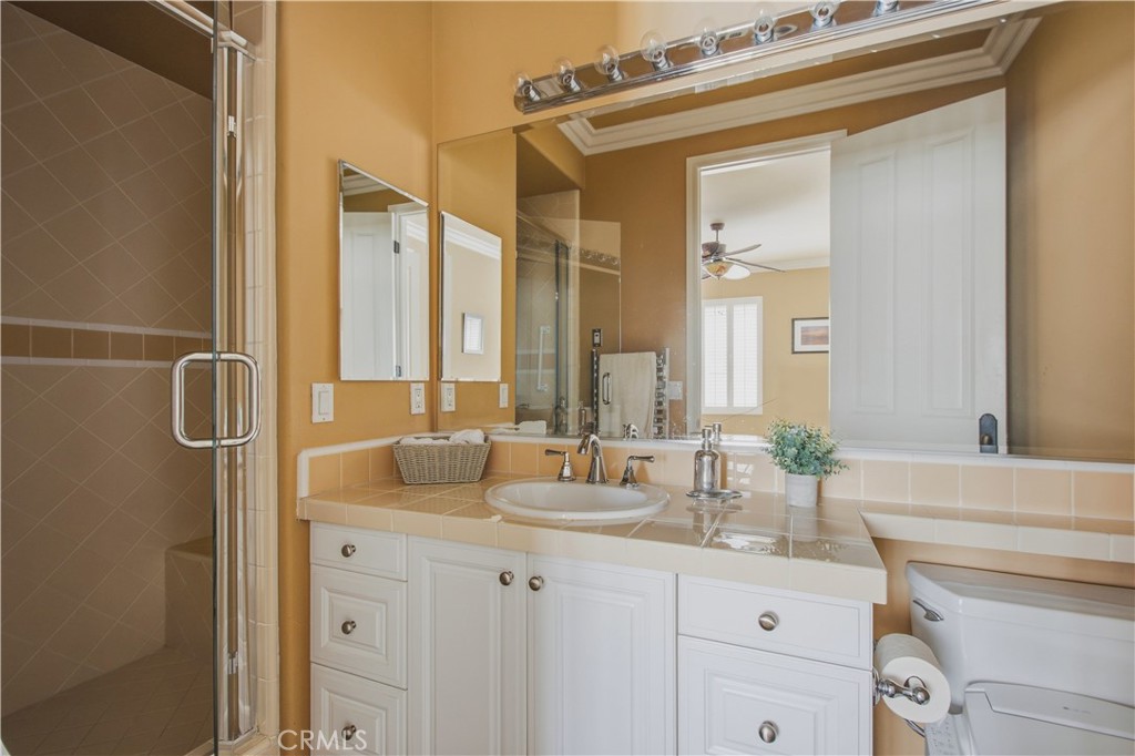 Upper-level 2nd Ensuite bathroom including glass door enclosed walk-in shower, white vanity with cabinetry, tile counter - 21322 Balerma, Huntington Beach CA 92648 - photo 31