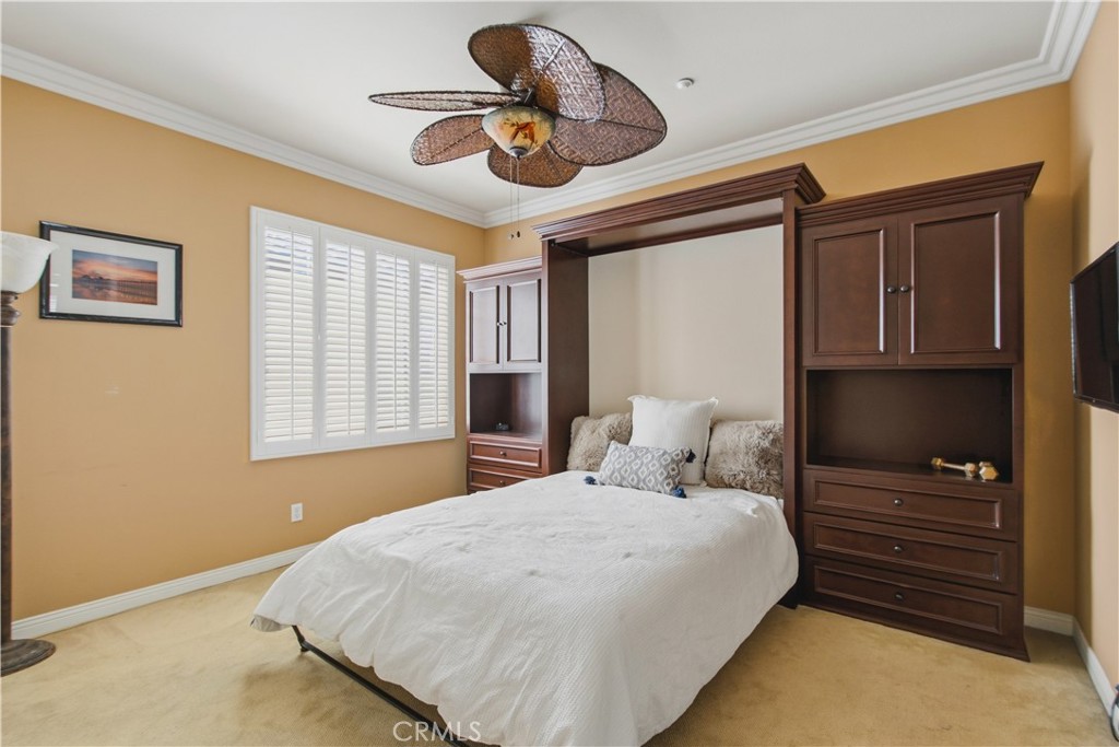 Upper-level 2nd Ensuite bedroom with carpet, crown molding, ceiling fan with light, plantation shutters, custom dark woo - 21322 Balerma, Huntington Beach CA 92648 - photo 32