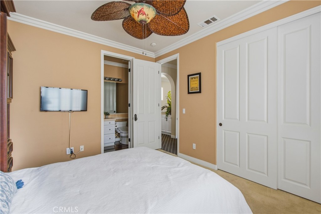 Upper-level 2nd Ensuite bedroom with carpet, crown molding, ceiling fan with light, closet, entry door into ensuite bath - 21322 Balerma, Huntington Beach CA 92648 - photo 33