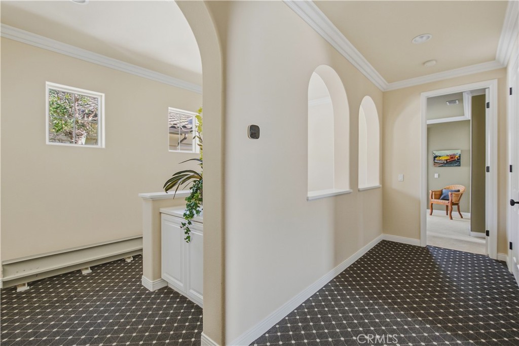 Top of stairs upper-level hallway with patterned carpet, crown molding, recessed lighting, arched wall openings, multi w - 21322 Balerma, Huntington Beach CA 92648 - photo 34