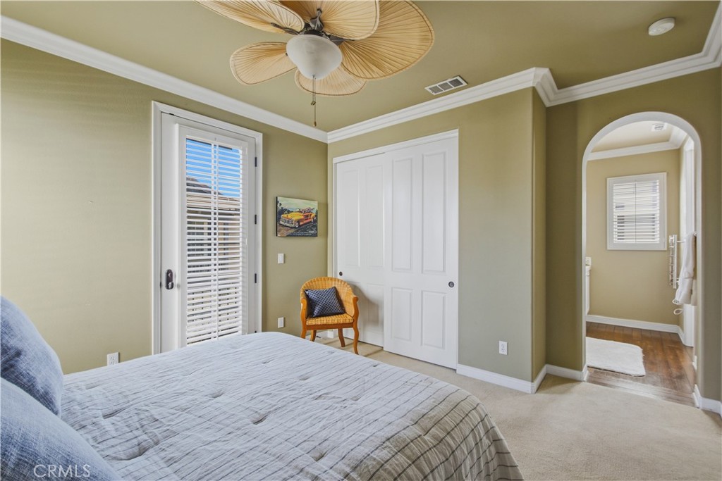 Upper-level 3rd ensuite bedroom with carpet, crown molding, ceiling fan with light, plantation shutters, French style do - 21322 Balerma, Huntington Beach CA 92648 - photo 37